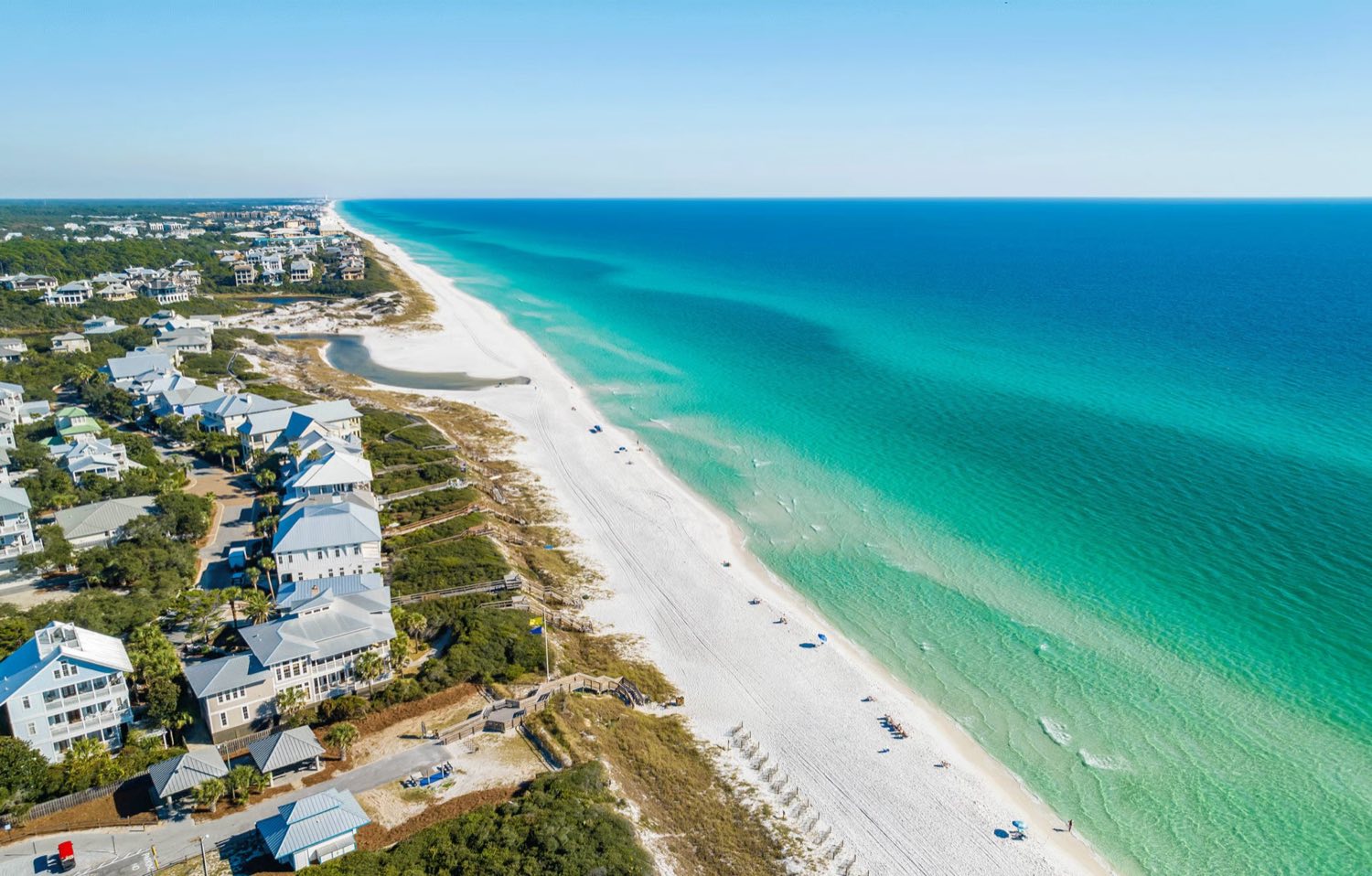 Aerial view of the white-sand beach, turquoise Gulf water, and beachfront homes along Scenic Highway 30A, Florida