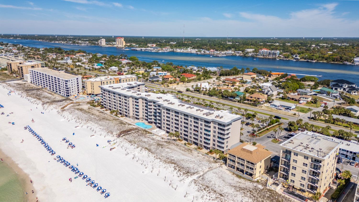 Aerial view of Okaloosa Island: beachfront condos and white sand along the Gulf, with the Santa Rosa Sound behind